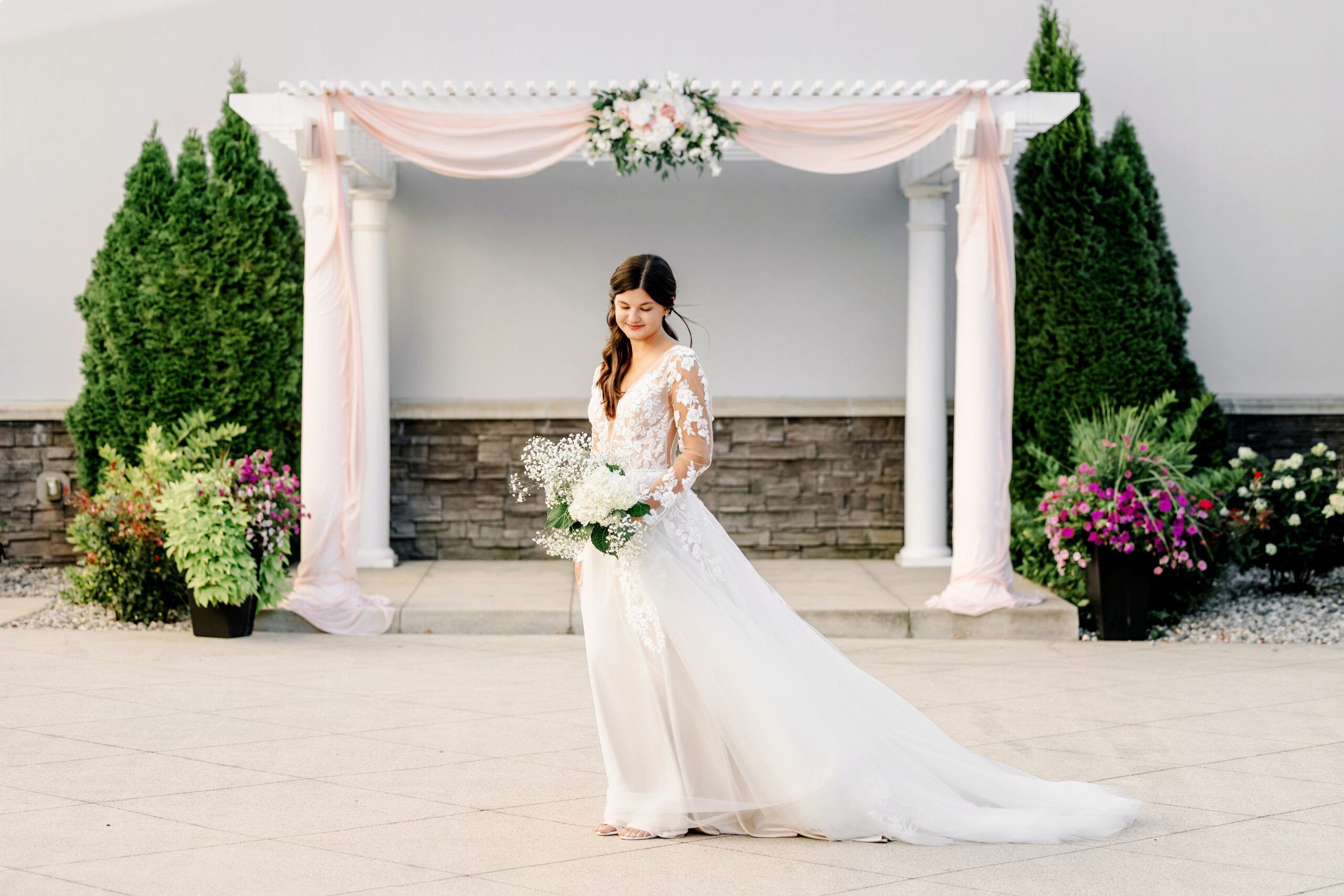 Bride in a lace wedding gown holding a white floral bouquet at a Ceruti’s wedding venue in Fort Wayne, Indiana.