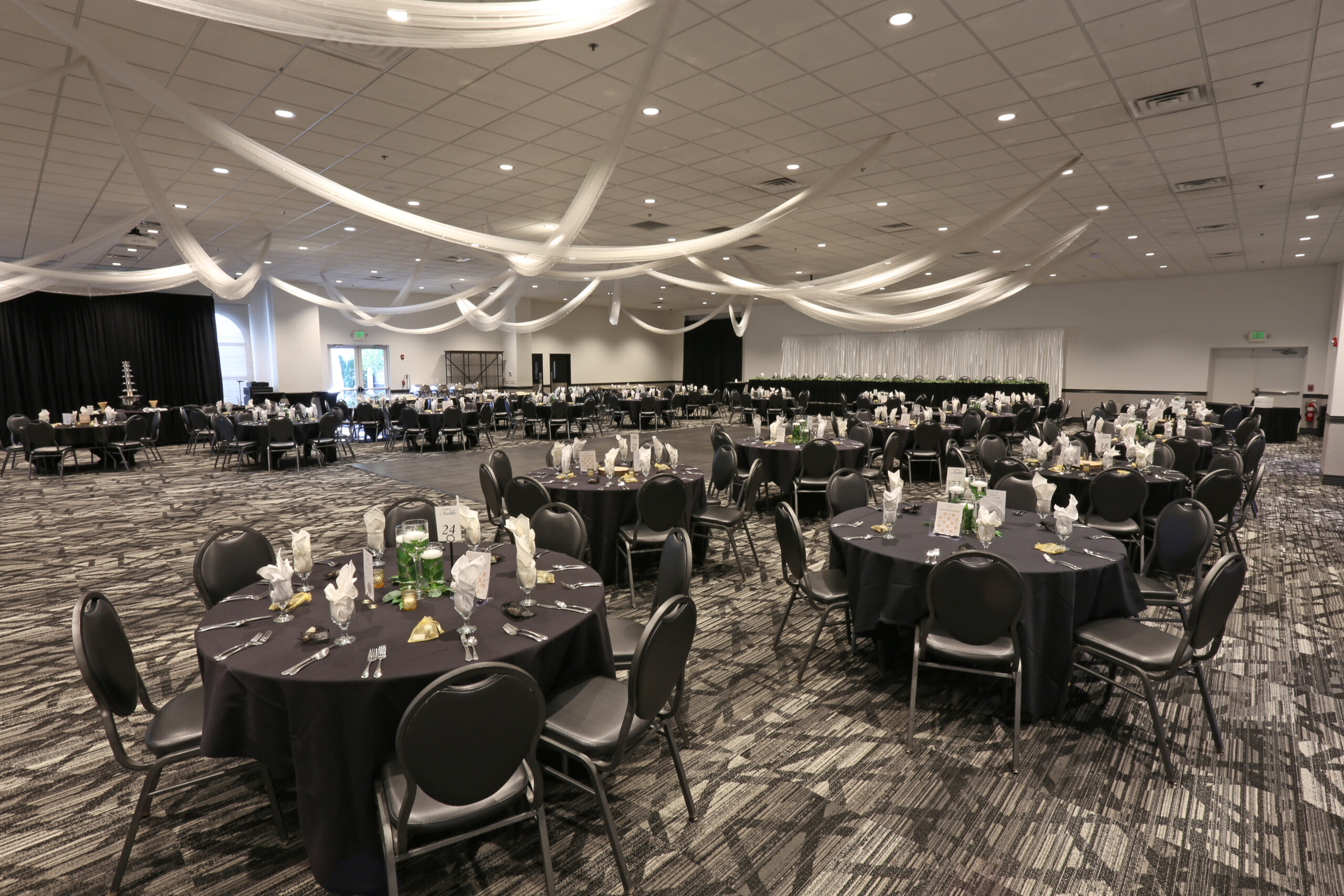 Spacious Diamond Room wedding reception venue at Ceruti’s Summit Park in Fort Wayne, Indiana, featuring elegant ceiling draping and decorated banquet tables