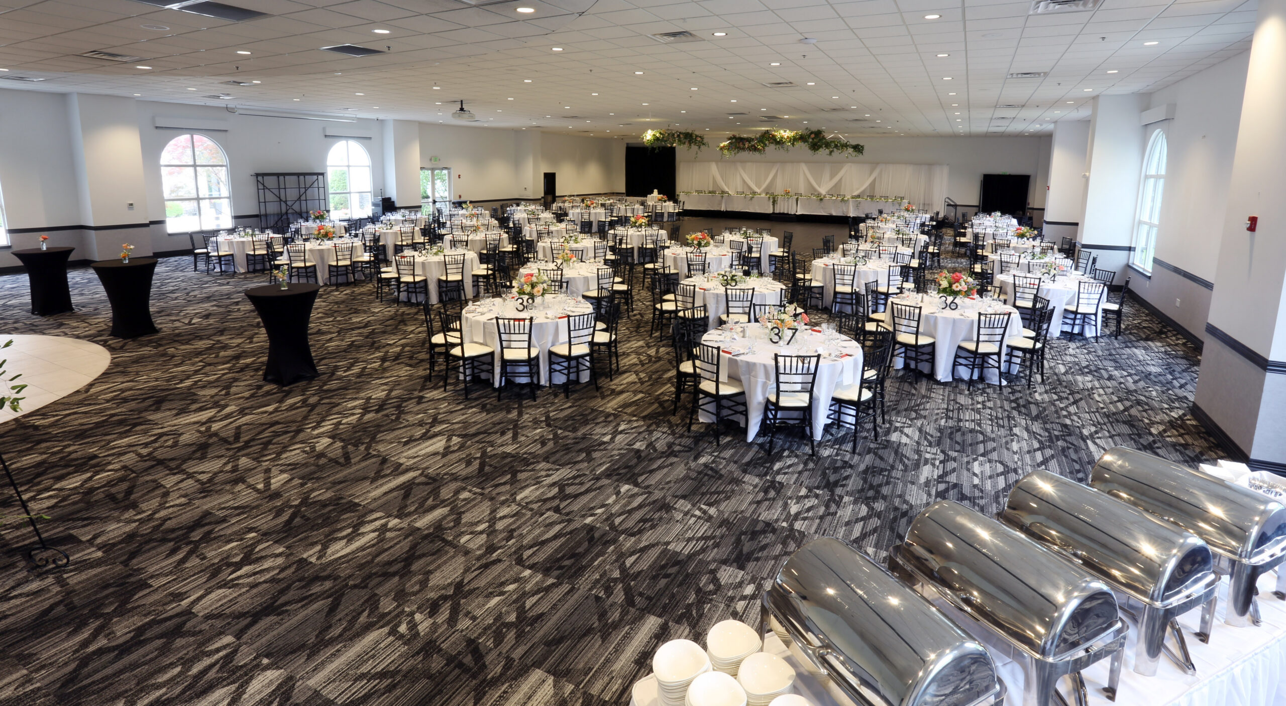 Spacious Fort Wayne wedding reception ballroom with round guest tables, white linens, floral centerpieces, and elegant seating at Ceruti’s.